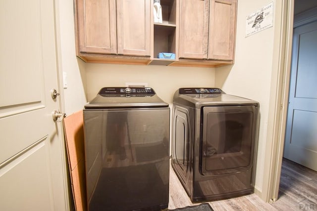 clothes washing area featuring cabinet space, independent washer and dryer, and light wood finished floors