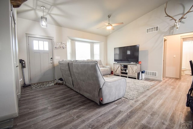 living area featuring vaulted ceiling, dark wood-style flooring, and visible vents