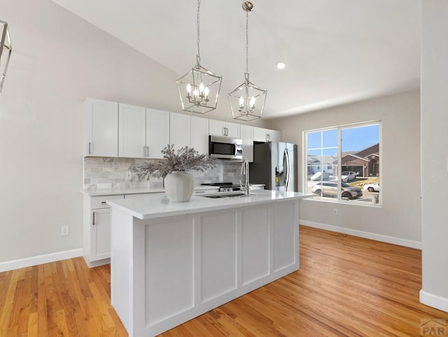 kitchen featuring stainless steel appliances, an island with sink, light countertops, and white cabinets