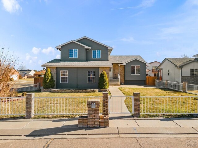 traditional-style home with a fenced front yard, a residential view, a front lawn, and brick siding