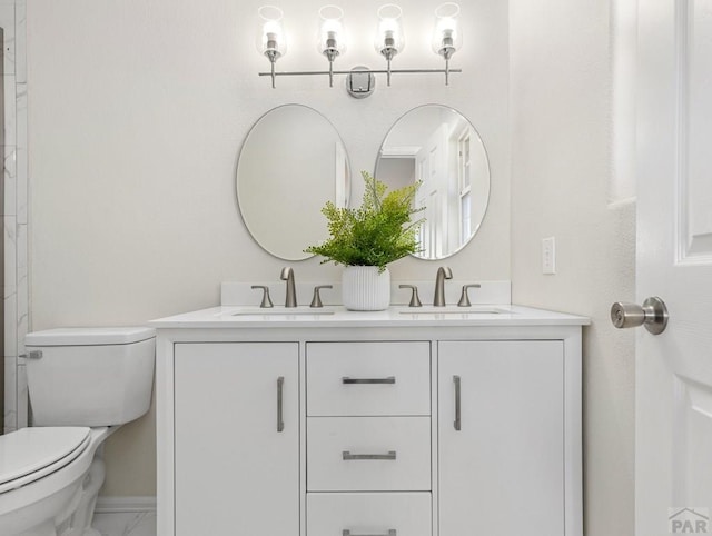 bathroom with marble finish floor, double vanity, a sink, and toilet