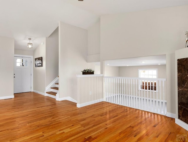 foyer entrance with lofted ceiling, wood finished floors, and baseboards