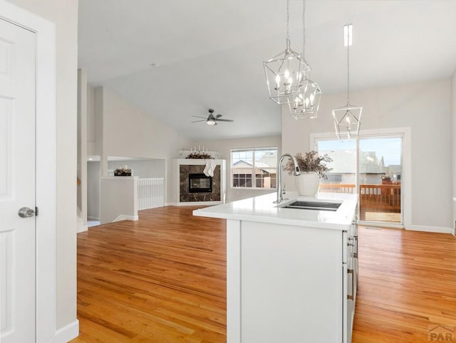 kitchen featuring pendant lighting, light countertops, open floor plan, a kitchen island with sink, and a sink