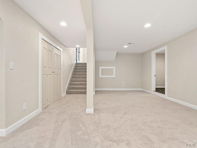 finished basement with stairs, recessed lighting, light carpet, and baseboards