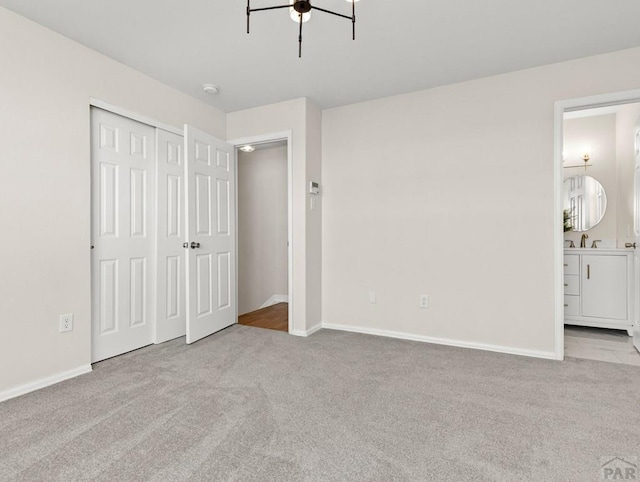 unfurnished bedroom with connected bathroom, light colored carpet, a ceiling fan, baseboards, and a closet