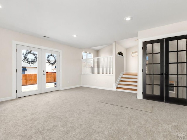 spare room featuring carpet floors, stairs, and french doors