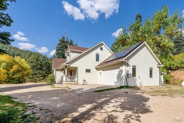 back of property featuring driveway, covered porch, and solar panels