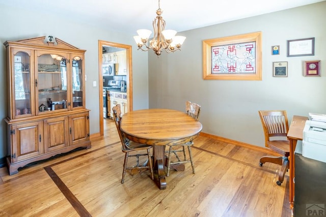 dining space with baseboards, an inviting chandelier, and light wood-style floors