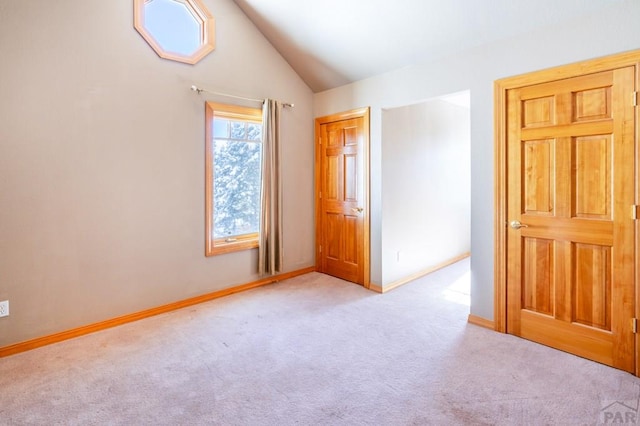 unfurnished bedroom featuring vaulted ceiling, baseboards, and light colored carpet