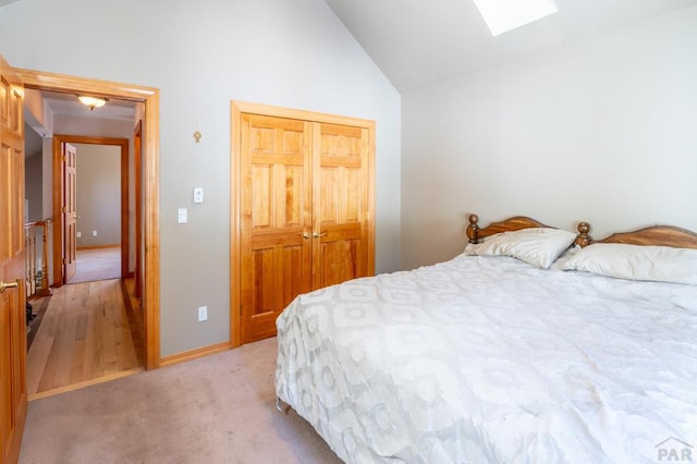 bedroom featuring vaulted ceiling with skylight, a closet, and light carpet