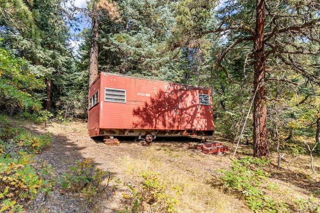 view of home's exterior with a storage shed, dirt driveway, and an outdoor structure