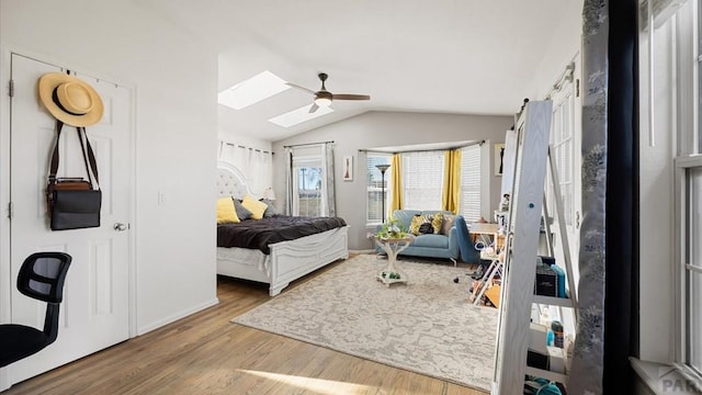 bedroom with vaulted ceiling with skylight, ceiling fan, and wood finished floors