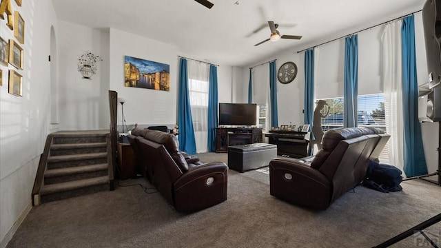 living area featuring arched walkways, a ceiling fan, carpet flooring, and stairway