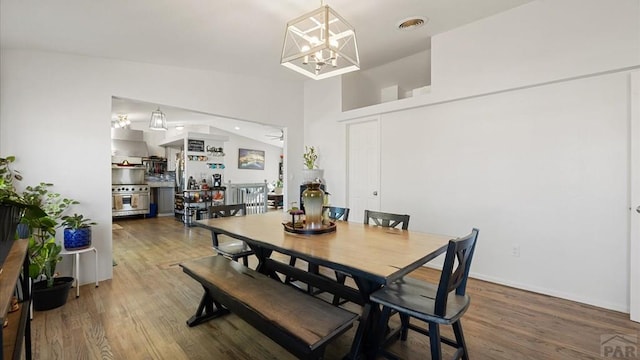 dining area with a notable chandelier, baseboards, vaulted ceiling, visible vents, and wood finished floors