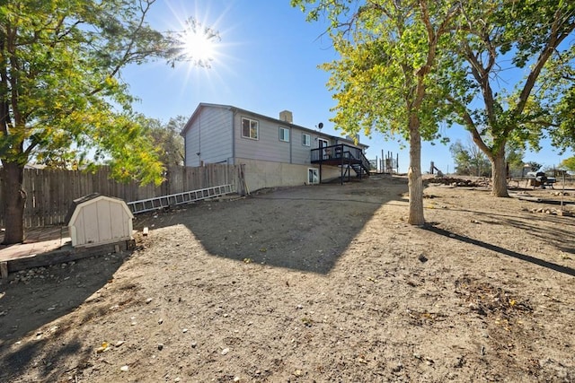 view of yard with stairs, a storage shed, an outbuilding, a deck, and fence