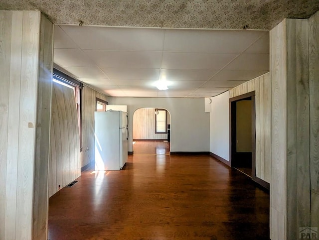 428 Elm Ave, Las Animas, CO 81054 - unfurnished room featuring arched walkways, dark wood finished floors, wooden walls, and a drop ceiling