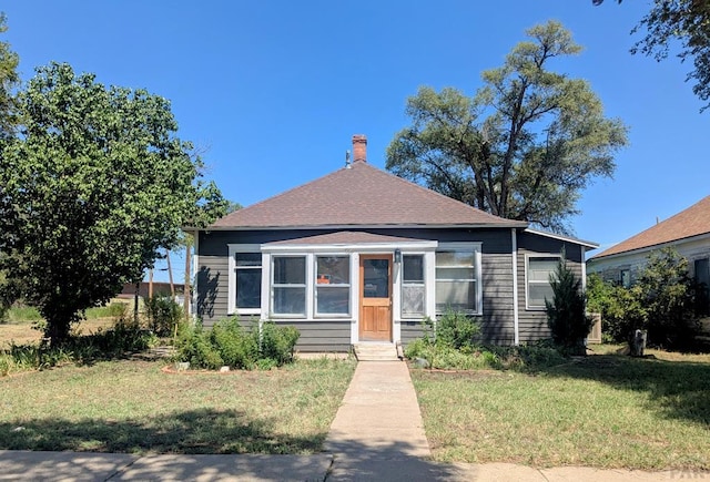 428 Elm Ave, Las Animas, CO 81054 - view of front facade featuring a front yard, a chimney, and a shingled roof