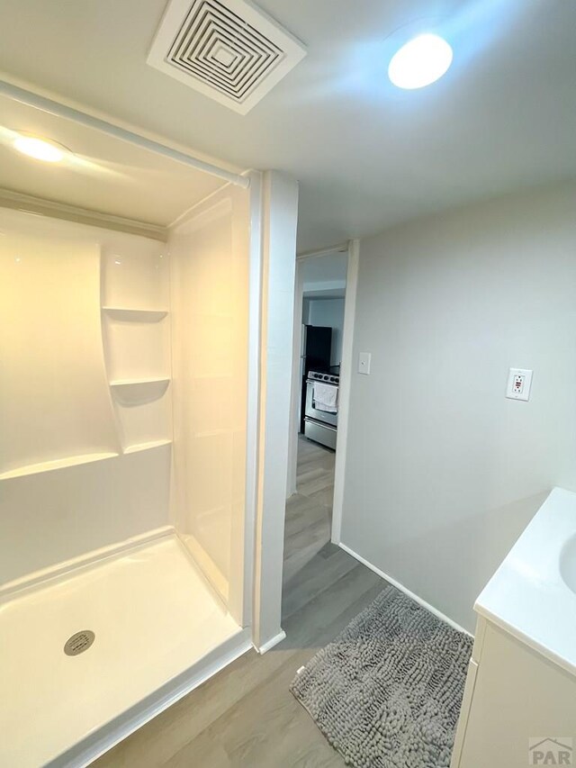 full bathroom with visible vents, a stall shower, vanity, wood finished floors, and baseboards