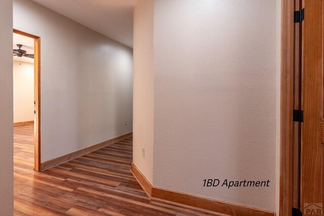 hallway featuring wood finished floors and baseboards