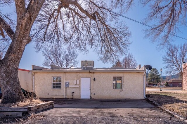 back of house featuring central AC and stucco siding