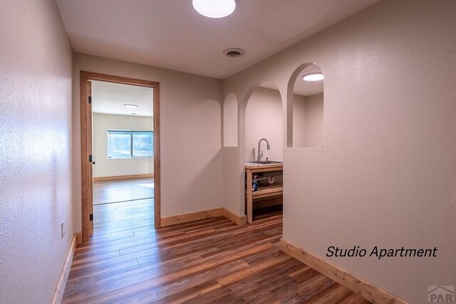 hall featuring visible vents, dark wood finished floors, and baseboards