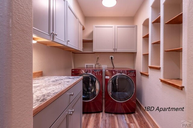 washroom featuring light wood finished floors, washer and clothes dryer, and cabinet space