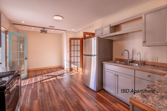 kitchen with range, dark wood-type flooring, freestanding refrigerator, open shelves, and a sink