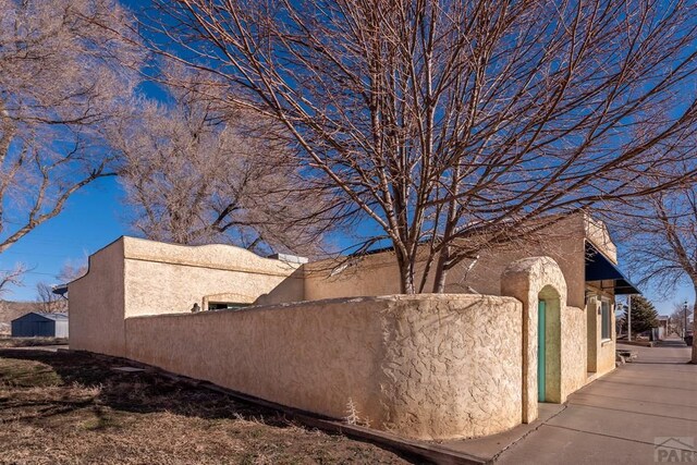 view of side of home featuring a fenced front yard and stucco siding