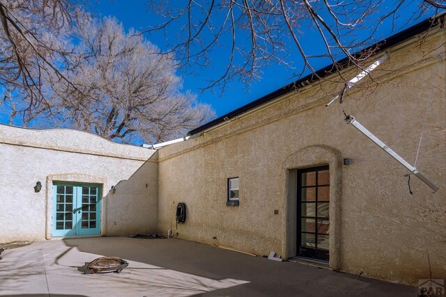 rear view of house featuring stucco siding, a patio area, and french doors