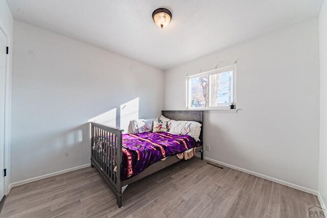 bedroom with light wood finished floors and baseboards