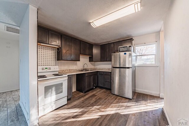 kitchen with light countertops, white electric range, freestanding refrigerator, a sink, and dark brown cabinets