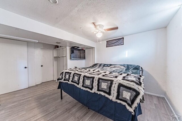 bedroom with a textured ceiling, a ceiling fan, and light wood-style floors