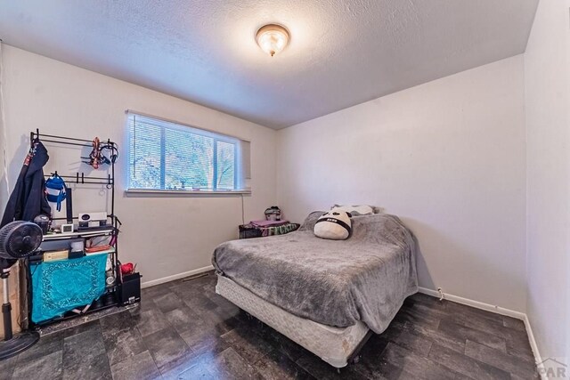 bedroom with a textured ceiling and baseboards