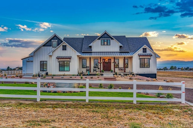 modern farmhouse style home featuring metal roof, a fenced front yard, covered porch, roof with shingles, and a standing seam roof