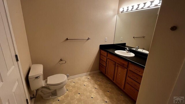 bathroom with baseboards, vanity, toilet, and tile patterned floors