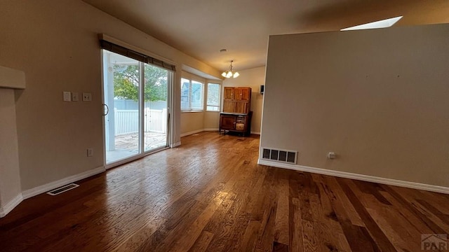 unfurnished living room featuring dark wood-type flooring, visible vents, and baseboards