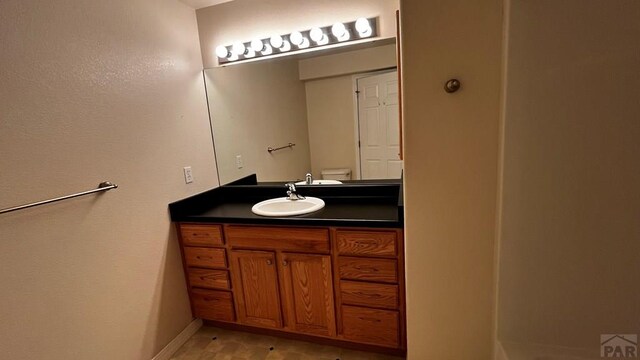 bathroom featuring toilet, baseboards, and vanity