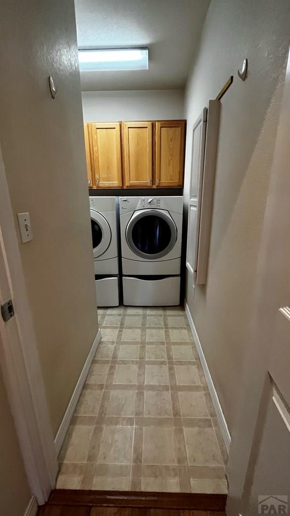 laundry room featuring baseboards, cabinet space, and washer and dryer