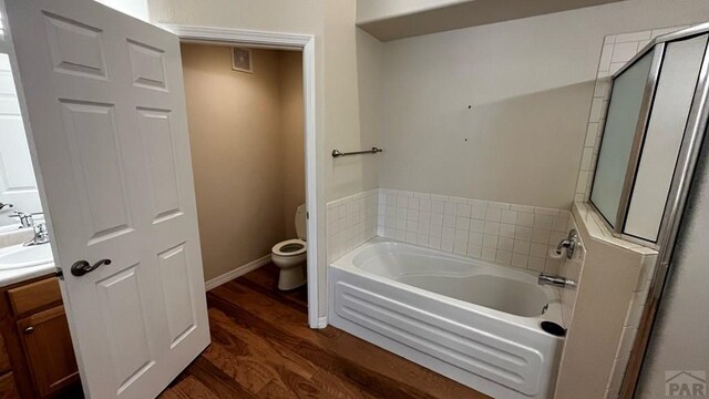 bathroom with toilet, wood finished floors, vanity, a shower stall, and a bath