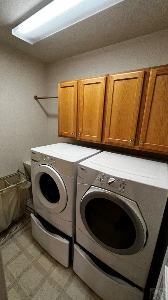 washroom with light floors, washing machine and clothes dryer, and cabinet space