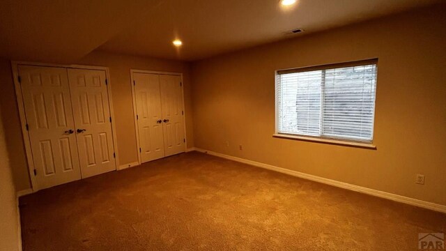 unfurnished bedroom featuring visible vents, baseboards, carpet flooring, two closets, and recessed lighting