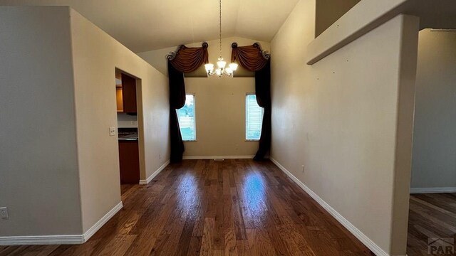 unfurnished dining area with a chandelier, vaulted ceiling, dark wood finished floors, and baseboards