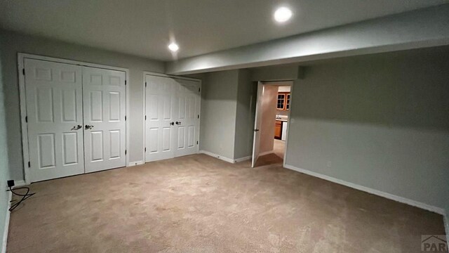 unfurnished bedroom featuring baseboards, carpet floors, recessed lighting, and multiple closets