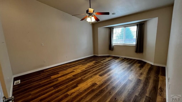 spare room featuring dark wood-style floors, a ceiling fan, visible vents, and baseboards