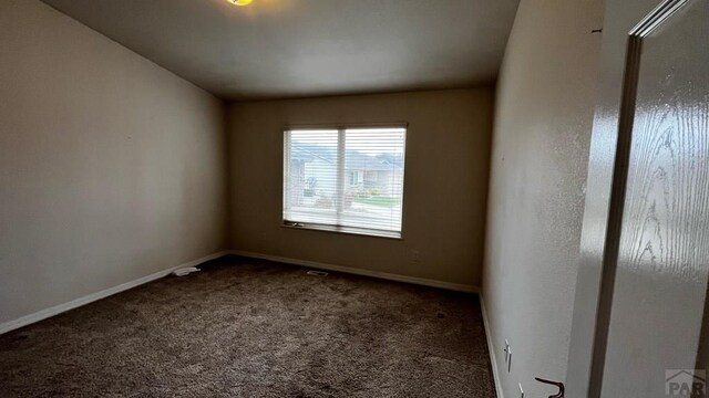 unfurnished room featuring baseboards and dark carpet