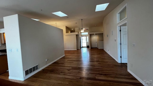 interior space with a skylight, baseboards, visible vents, and dark wood-type flooring