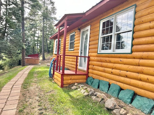 view of property exterior with log veneer siding and a hot tub