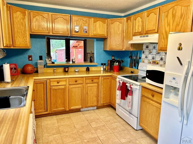 kitchen with a textured ceiling, under cabinet range hood, white appliances, light countertops, and brown cabinetry