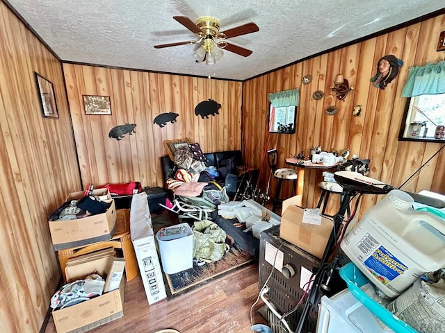 miscellaneous room featuring a textured ceiling, ornamental molding, dark wood-style floors, and wooden walls