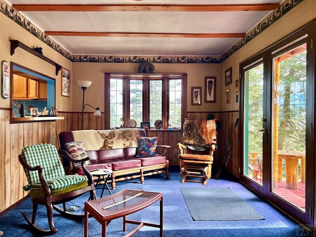 sitting room featuring a wealth of natural light, carpet, wainscoting, and wooden walls